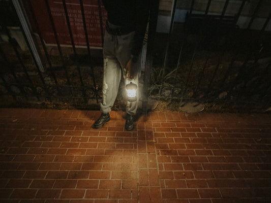 A tour guide holding a lantern illuminating the brick pavement in the Gaslamp District at night.